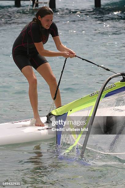 Germany, : A young woman is trying to surf.