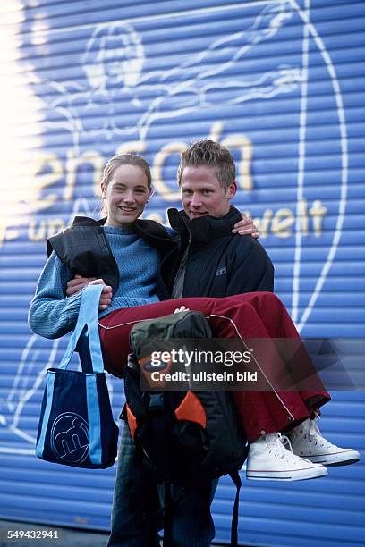 Germany: Free time.- Portrait of a two young persons; the boy is carriing the girl on his hands.