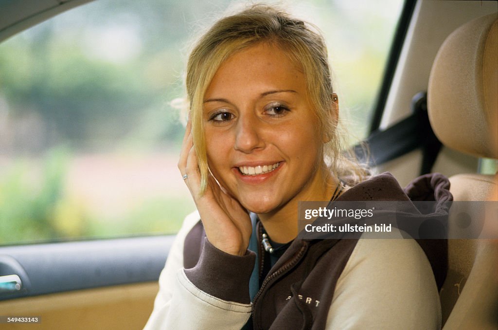 DEU, Germany: Free time.- Portrait of a young woman sitting in a car.