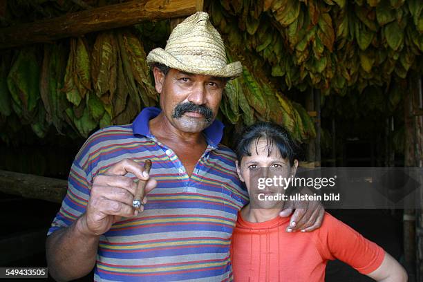 Cuba, San Luis: Portrait of a storeman and his wife; he is guarding the tobaco leaves which are hung up for driing.