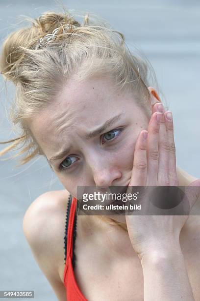 Germany, Cologne: Free time.- Portrait; a young woman holding her hand at her cheek.