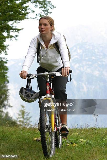 Germany, : A young woman riding through the countryside with her mountainbike.