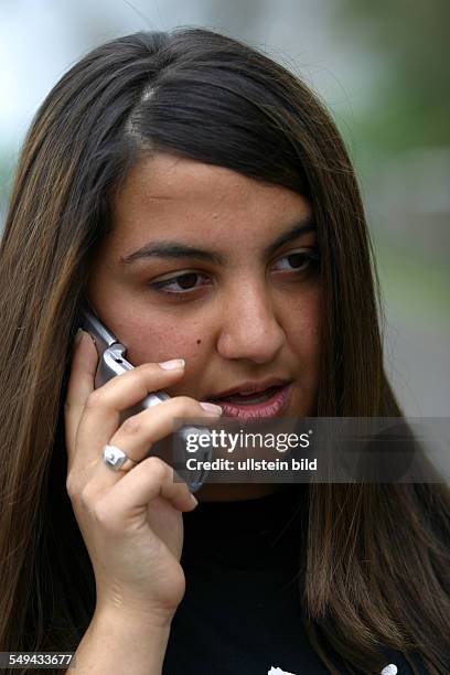 Germany, : Free time.- Portrait of a young woman; she is phoning with her mobile phone.