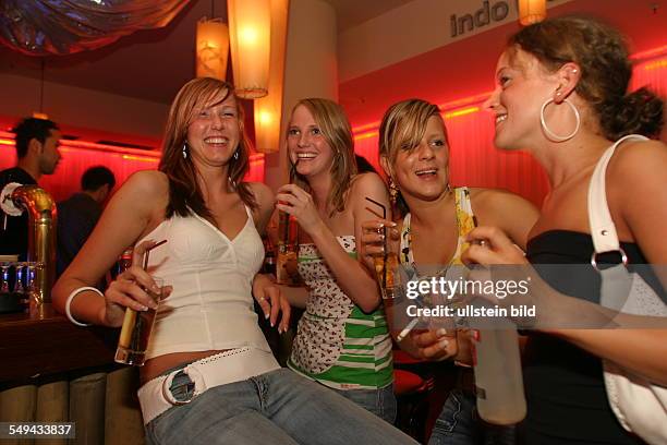 Germany: Young persons at nightlife.- Four friends at the bar; alcoholic mixed drinks.