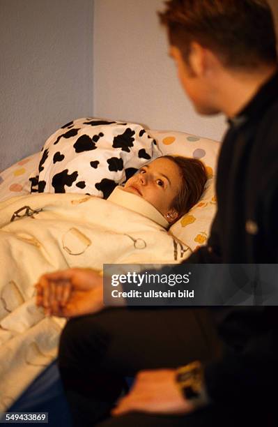 Deutschland: Freizeit.- Jugendliche zuhause; ein Junge sitzt am Bett seiner kranken Freundin. L DEU, Germany: Free time.- Youth at home; a boy is...