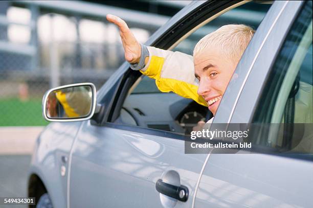 Germany: Free time.- A young man in a car; he is waving out of the window.