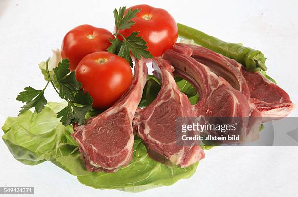 Lebensmittel - Fleisch.- Rohe Rippchen auf Salat, mit Tomaten, Peperoni und Kraeutern.