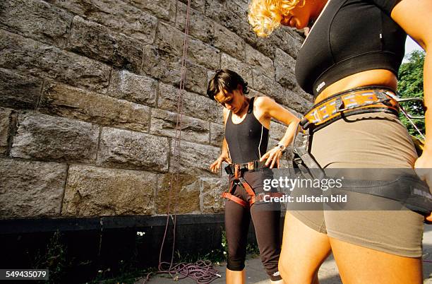 Germany: Free time.- Young women preparing for climbing; safety equipment.