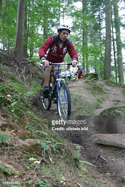 Germany, : A young man riding with his mountainbike through the wood.