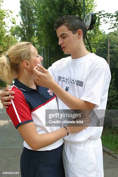 Germany, : Two young persons in tennis kit.- They embrace each other and he strokes her cheek.