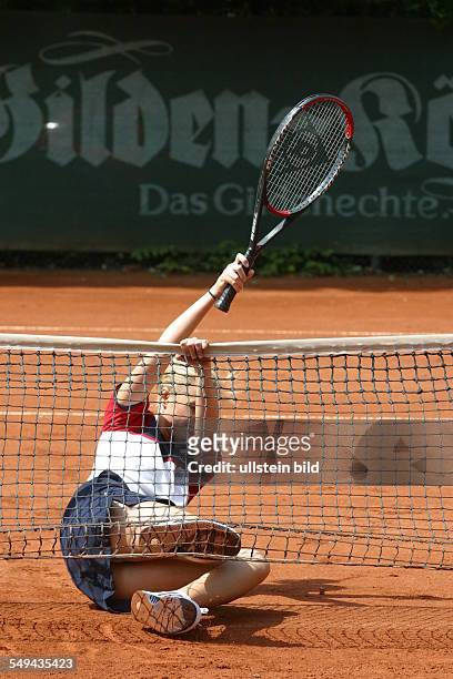 Germany, : A young woman on a tennis court; she is slipped.