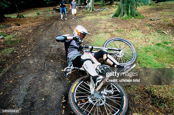 Germany: Free time.- Bicyclists in the wood, one is falling.