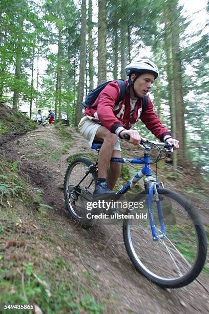 Germany, : A young man riding with his mountainbike through the wood.