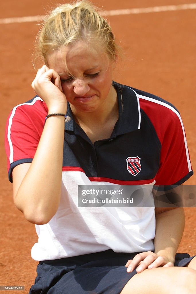 DEU, Germany, 13.11.2003: Portrait of a young woman on a tennis court.- She is sitting on the court crying.