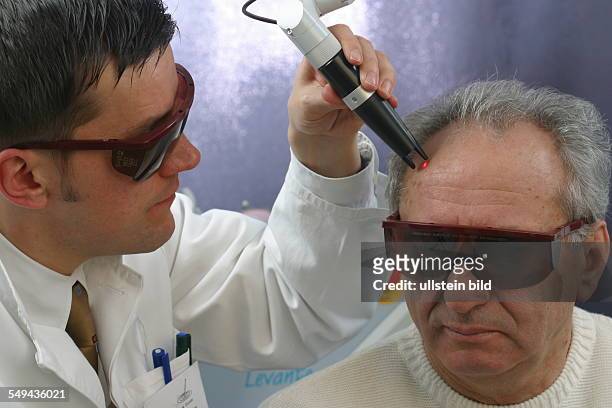 Germany, Essen, medicine physicist and non-medical practitioner Holger May, manager of the Laser Forum Essen. A patient during a laser treatment. Age...