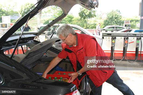 Germany, Kalkar, : Filling station.- A man packing his drinks boxes into the boot.