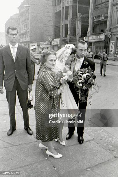 Bride and groom at Friedrichstrasse / Checkpoint Charlie in Berlin-Kreuzberg are looking towards East Berlin