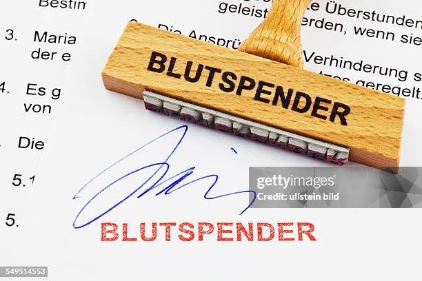 Ein Stempel aus Holz liegt auf einem Dokument. Deutsche Aufschrift: Blutspender