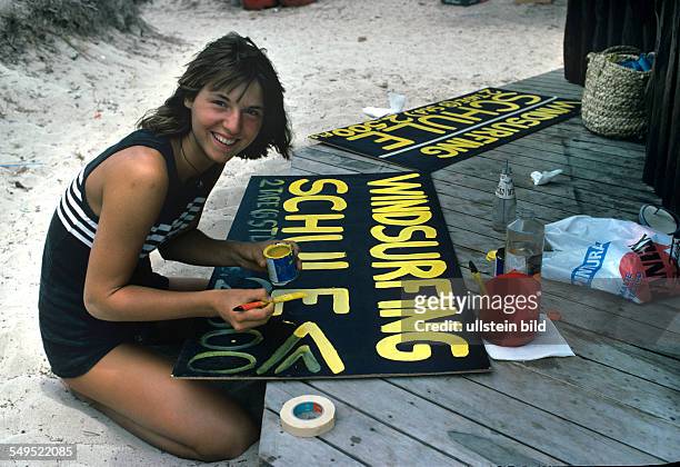 Harry Valeriens Tochter Tanja im Urlaub auf Ibiza, beschriftet ein Schild in der Surfschule