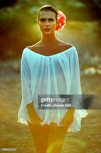 Hippie Mädchen mit roten Bougainvillea-Blumen im Haar, Strandkleidung, Ibiza