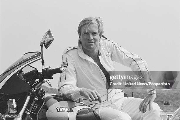 English actor Nicky Henson, who plays the character of Allan Hearshner in the television series 'Driving Ambition', pictured sitting on a Yamaha...