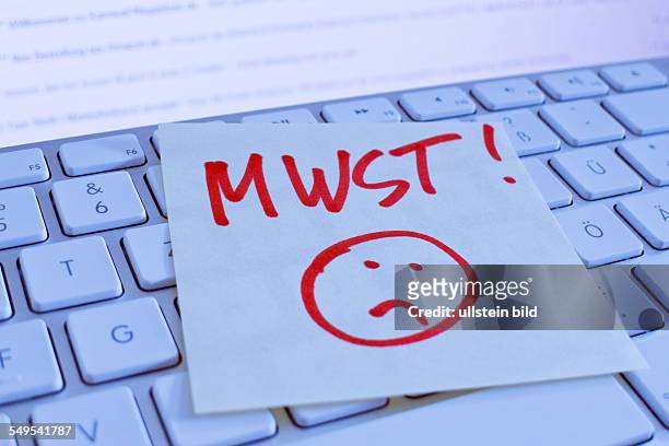 Ein Notizzettel liegt auf der Tastatur eines Computers zur Erinnerung: Mehrwertsteuer, MWSt