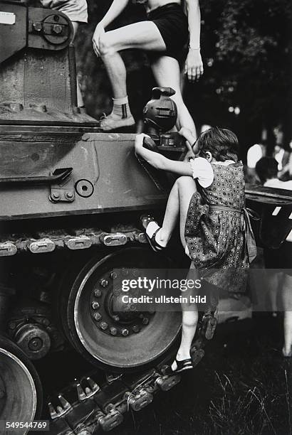 Germany, Hamburg, girl climbing on a military tank of the German Army