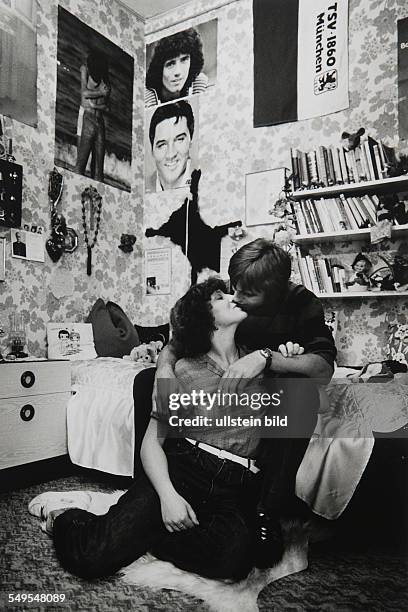 Germany, young couple at home kissing.