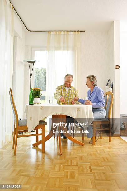 Bonn: Living in old age: Seniors couple playing ludo board game at home.