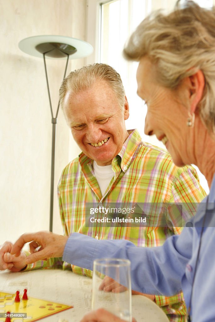 DEU, GERMANY, Bonn: Living in old age: Seniors couple playing ludo board game at home.