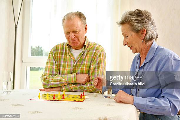 Bonn: Living in old age: Seniors couple playing ludo board game at home.