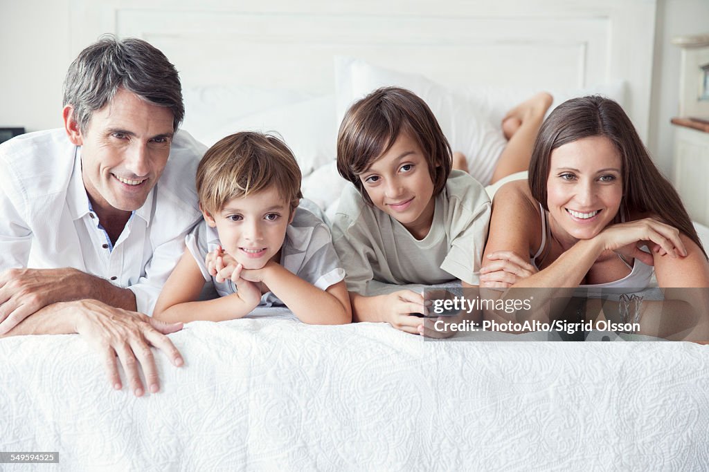 Family watching TV on bed, portrait