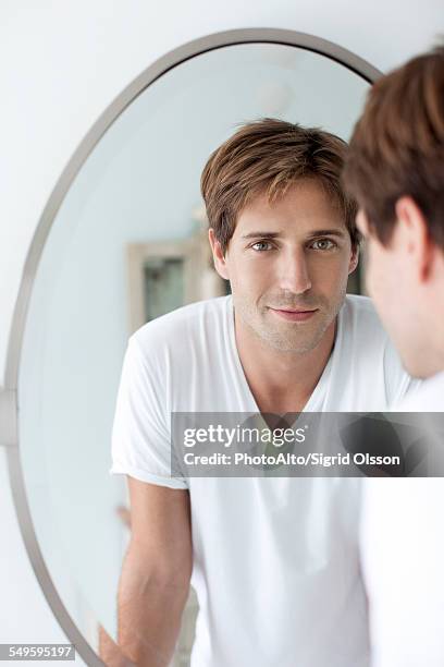 man looking at self in mirror - man in front of mirror foto e immagini stock