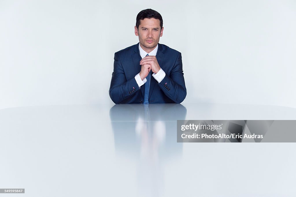 Confident businessman seated at table, portrait
