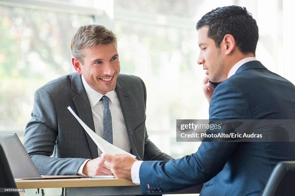 Businessmen discussing documents in meeting