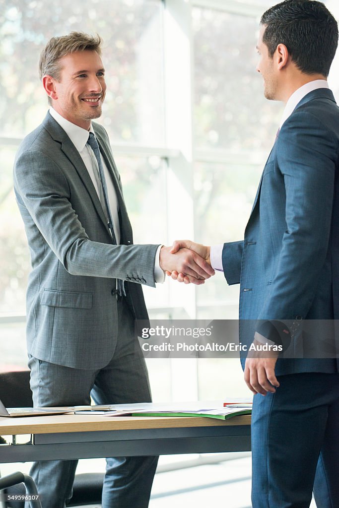 Businessmen shaking hands in office