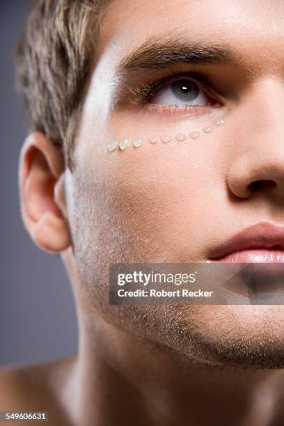 young man with cream around his eye - man eye cream stock pictures, royalty-free photos & images