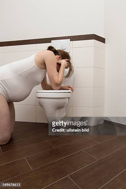 Young pregnant woman, 35 years old, feeling sick on a toilet.