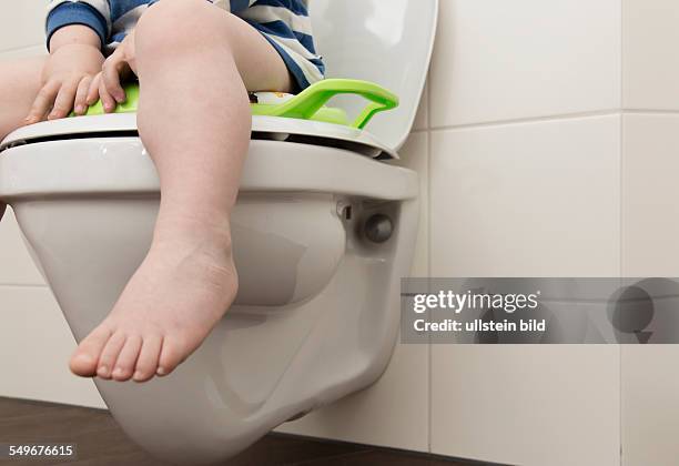 Year old boy with childrens seat on a toilet.
