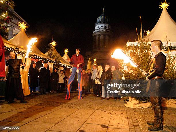 Weihnachtsmarkt auf dem Gendarmenmarkt, Feuerkuenstler und Jongleur, im Hintergrund die Kuppel des Franzoesischen Dom