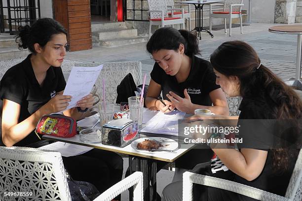 Türkei, Antalya, Schuelerinnen in Schulkleidung arbeiten in einem Cafe