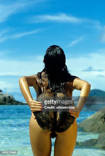 Nude woman posing with nut from the Coco de Mer, island of Praslin in the Seychelles