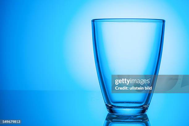 Ein leeres Glas steht vor einem blauen Hintergrund.