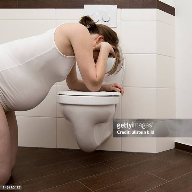 Young pregnant woman, 35 years old, feeling sick on a toilet.