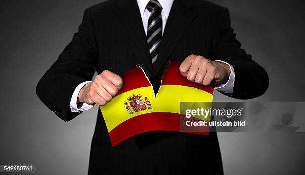 Man in a suit tearing apart the national flag of Spain.