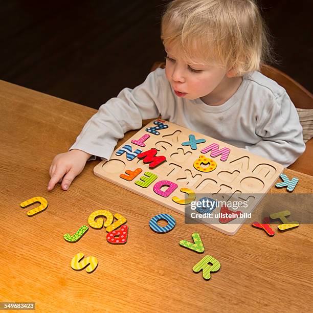 Boy, 2 years old, playing with an ABC puzzle