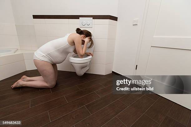 Young pregnant woman, 35 years old, feeling sick on a toilet.