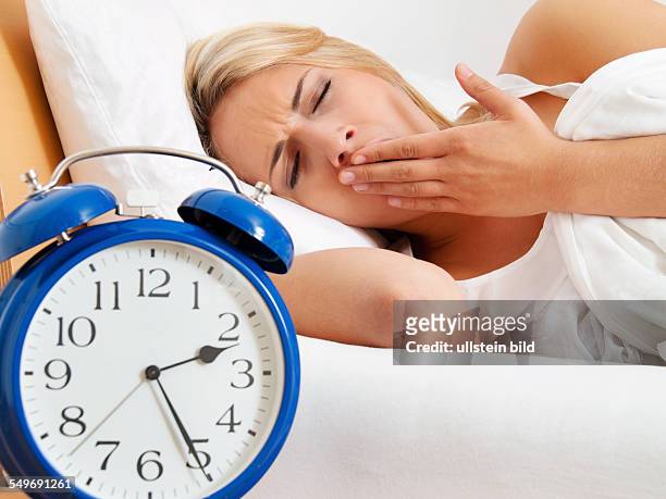 Schlaflosigkeit, Frau kann nicht schlafen. Wecker zeigt fünf vor halbdrei