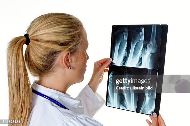 Eine junge Ärztin mit Stethoskop betrachtet ein Röntgenbild