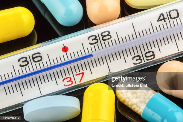 Ein Fieberthermometer und Tabletten. Symbolfoto für Grippe und Erkältungen